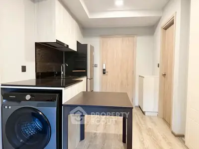 Modern kitchen with sleek appliances and compact dining area in a stylish apartment.