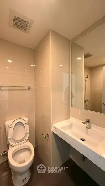 Modern bathroom with sleek fixtures and large mirror in a contemporary apartment.