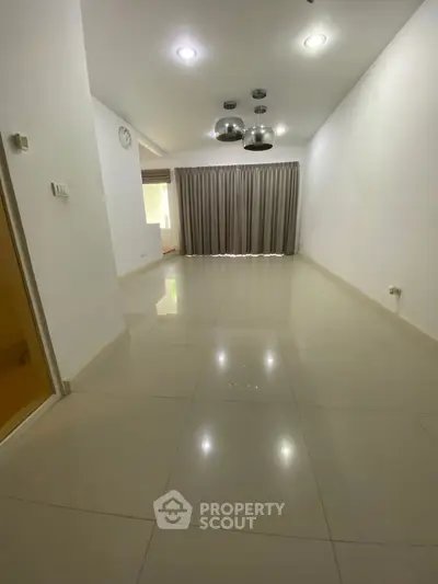 Spacious empty living room with modern lighting and tiled flooring
