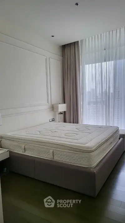 Spacious bedroom with large window and modern decor in high-rise apartment