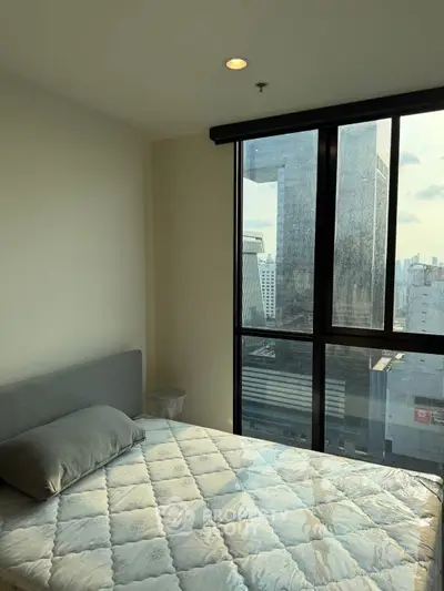 Modern bedroom with large window offering stunning city view in high-rise apartment.