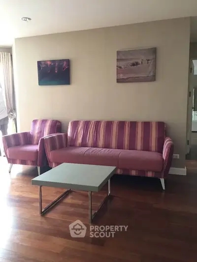 Cozy living room with striped sofa and armchair, wooden flooring, and modern decor.