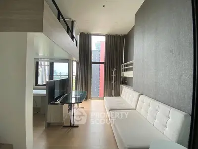 Modern loft apartment with high ceilings and large windows offering city views.