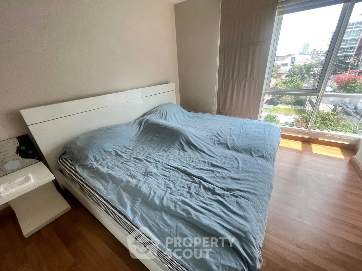 Spacious bedroom with large window offering city views and natural light.