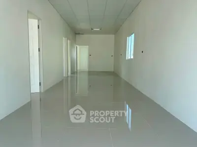 Spacious empty room with glossy tiled floor and white walls, ideal for customization.