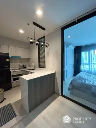 Modern kitchen with sleek design and adjacent cozy bedroom in stylish apartment.