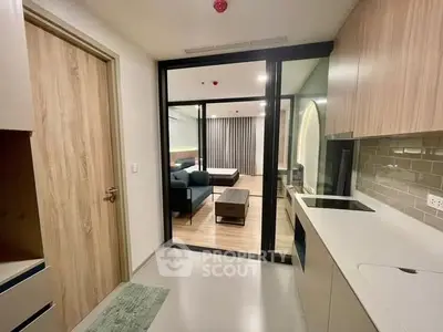 Modern open layout kitchen leading to a stylish living room with sleek furnishings.