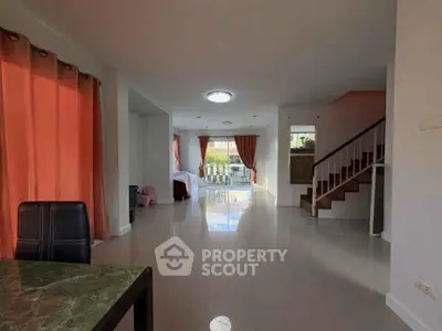 Spacious open-plan living room with large windows and modern staircase