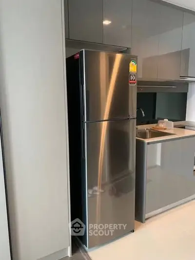 Modern kitchen with sleek stainless steel fridge and glossy cabinets.