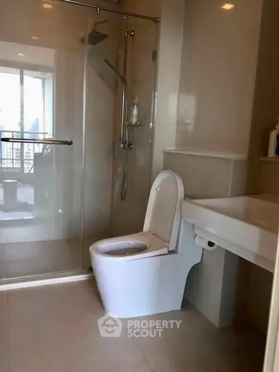 Modern bathroom with glass shower and city view window, ideal for urban living.
