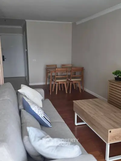 Modern living room with cozy sofa, wooden dining set, and stylish decor in a contemporary apartment.