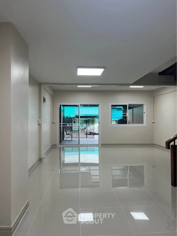 Spacious modern living room with glossy tiled floors and large windows.