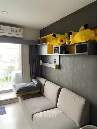 Modern living room with stylish gray sofa and playful decor, featuring plush toys and a balcony view.