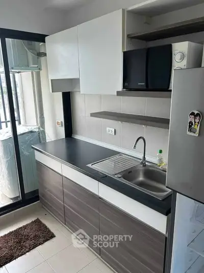 Modern kitchen with sleek cabinets and stainless steel appliances in a bright apartment.