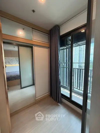 Modern bedroom with large mirrored closet and balcony view in high-rise apartment