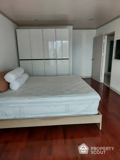 Spacious bedroom with polished hardwood floors and large built-in wardrobes, offering a serene and comfortable living space with ample natural light.