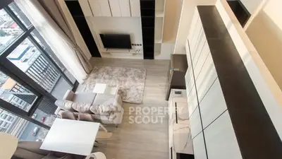 Modern living room with high ceiling and large windows offering city views.