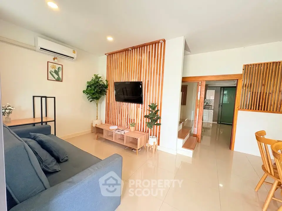 Modern living room with sleek design, featuring a cozy sofa and wall-mounted TV, perfect for relaxation.