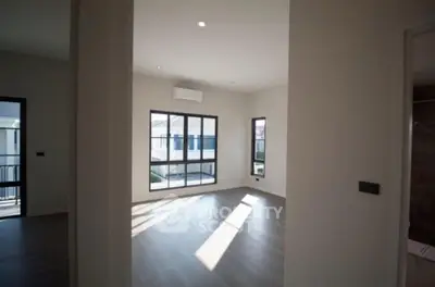 Spacious room with large windows and modern flooring, perfect for natural light.