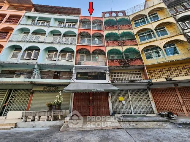 Colorful multi-story building with arched windows and balconies in urban setting.