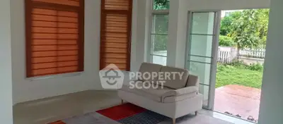 Bright living room with modern sofa and large windows overlooking a lush garden.
