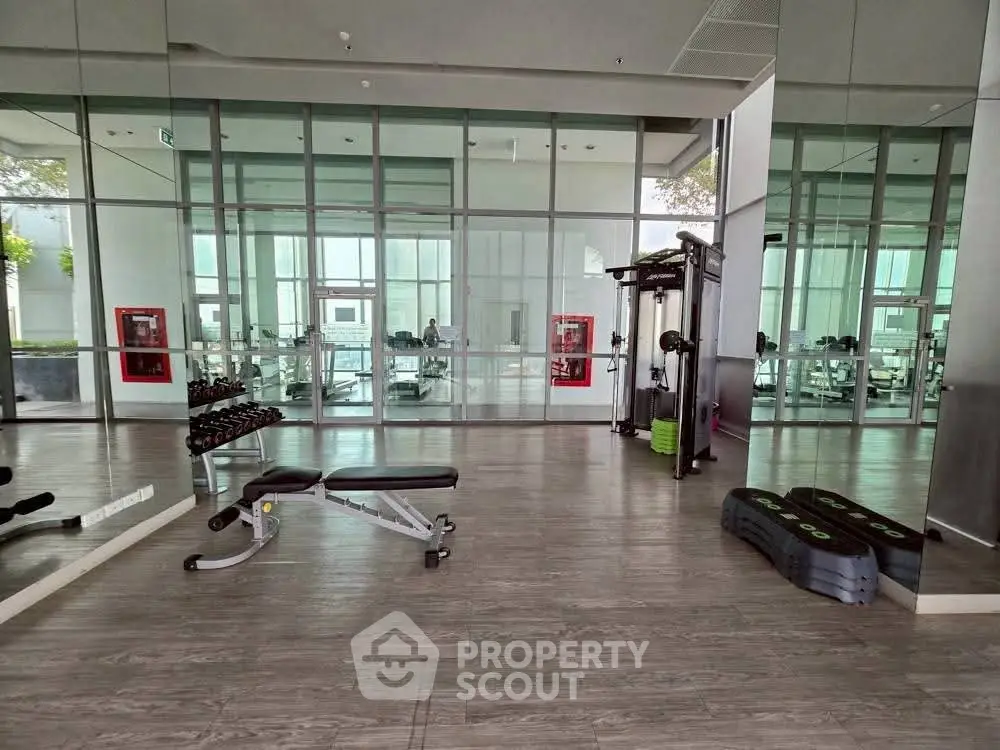 Modern gym with state-of-the-art equipment and mirrored walls in luxury residential building.