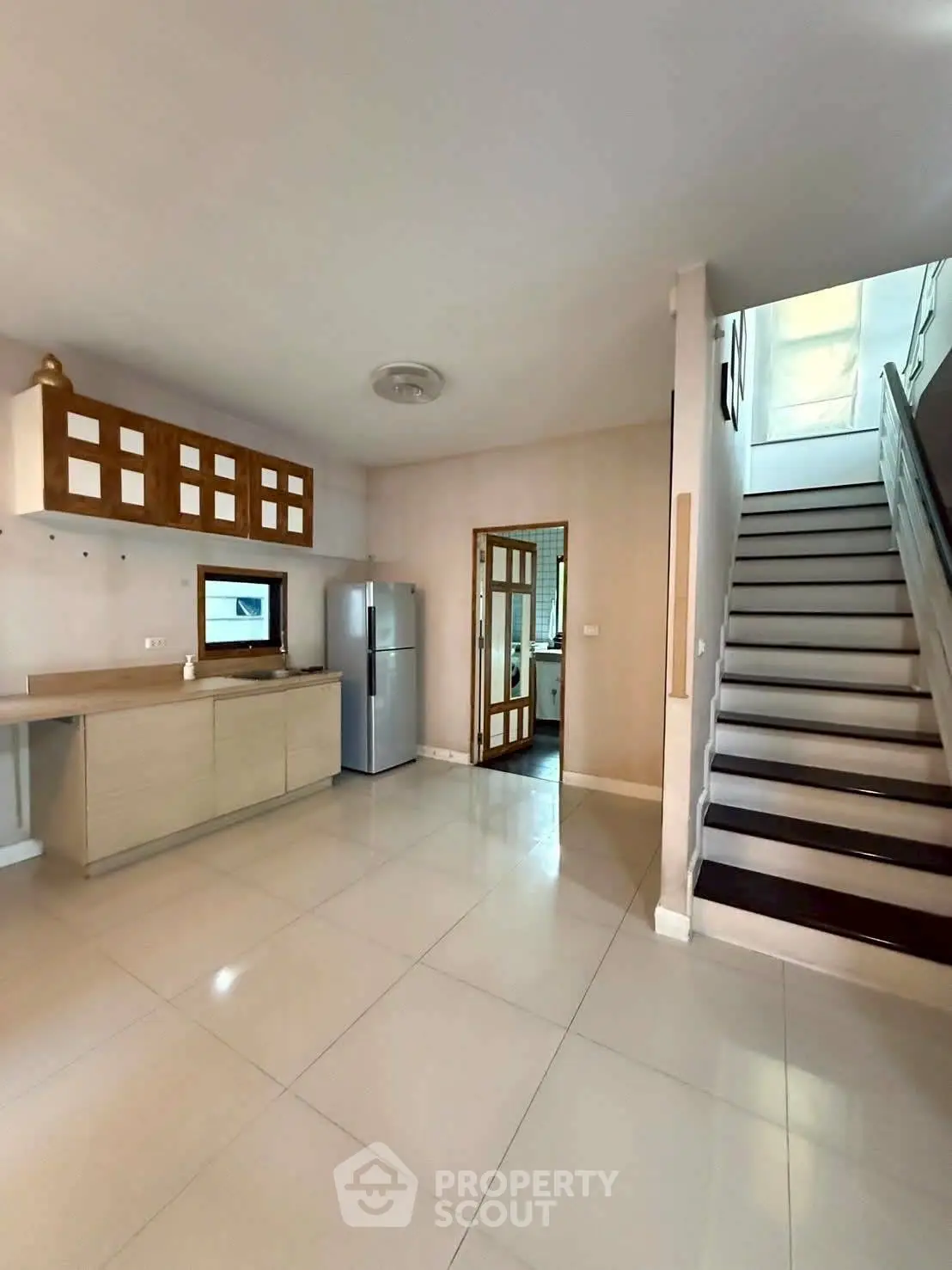 Spacious kitchen with modern appliances and sleek staircase in a contemporary home.