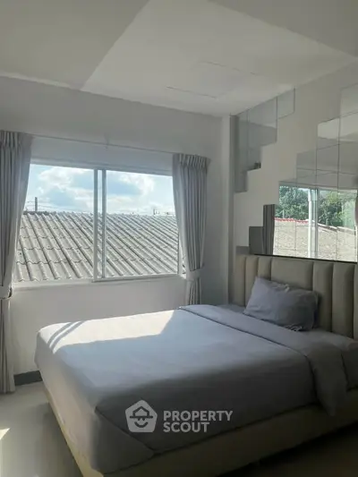 Bright and cozy bedroom with large window and modern decor, perfect for relaxation.