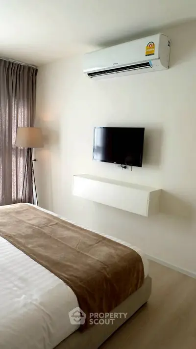 Modern bedroom with air conditioning and wall-mounted TV, featuring elegant decor and natural light.
