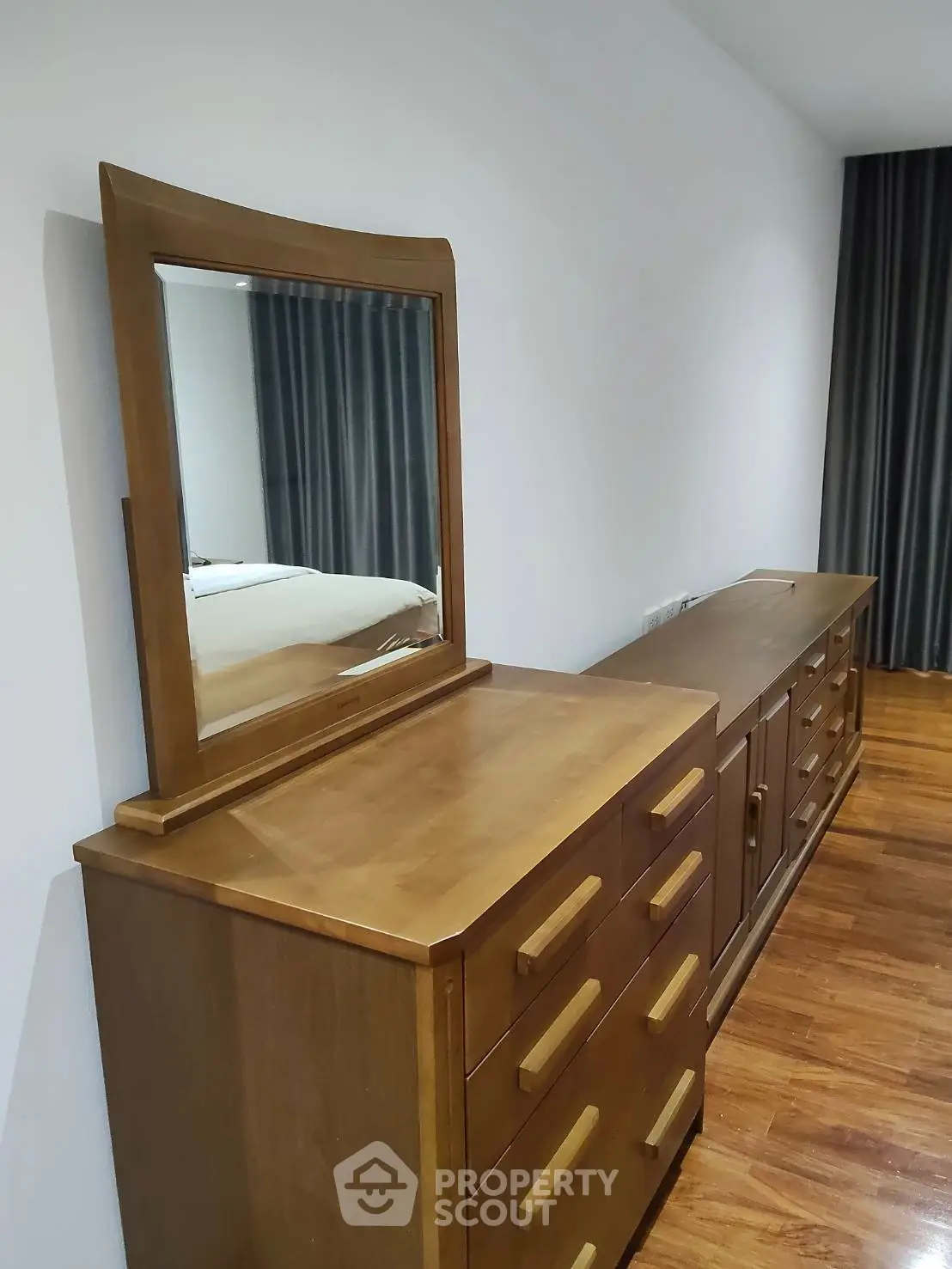 Spacious bedroom with elegant wooden furniture and polished hardwood floors.