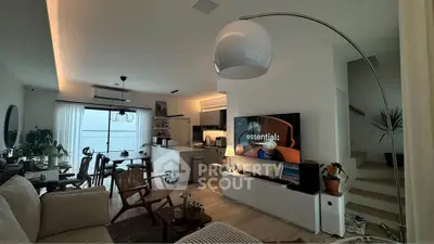 Modern living room with open kitchen, stylish decor, and natural light.