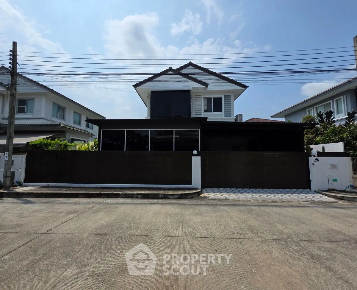 Modern two-story house with sleek design and spacious driveway in suburban neighborhood.