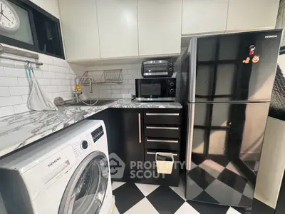 Modern kitchen with marble countertop, washing machine, and stainless steel appliances.