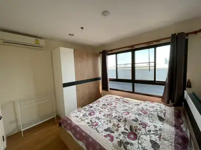 Cozy bedroom with large window and floral bedding in modern apartment