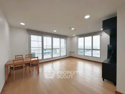 Spacious living room with large windows and wooden flooring in modern apartment.