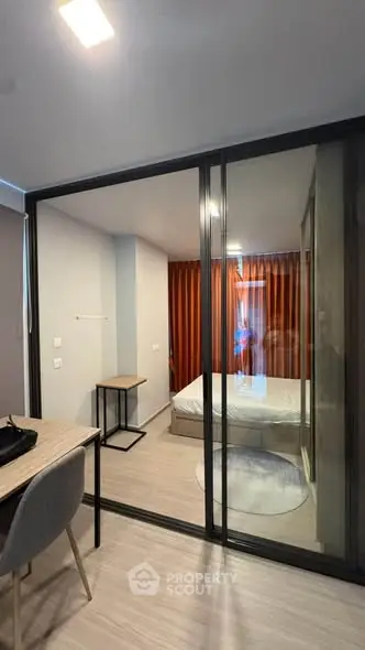 Modern studio apartment with glass partition, cozy bedroom, and stylish workspace.