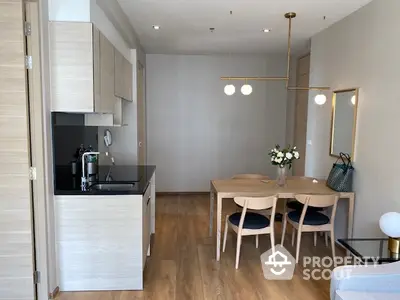 Modern open-layout kitchen and dining area with elegant lighting and wooden flooring.