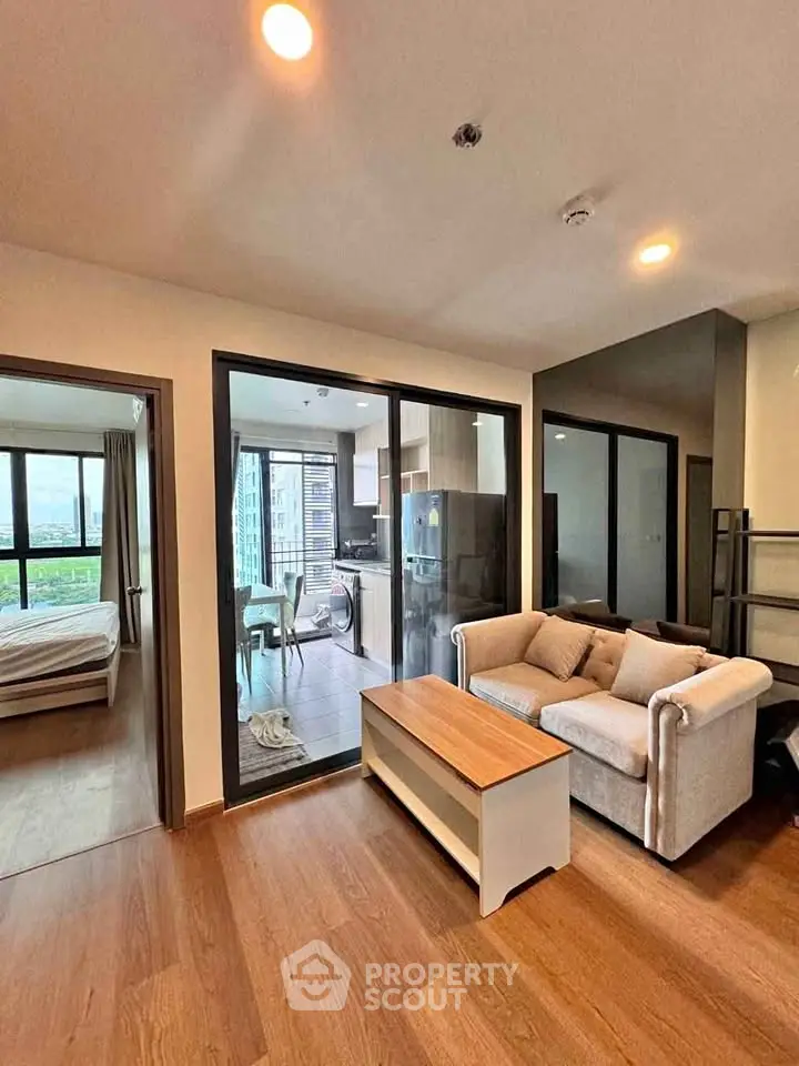 Modern apartment interior with cozy living room and open kitchen layout, featuring a stylish sofa and wooden flooring.