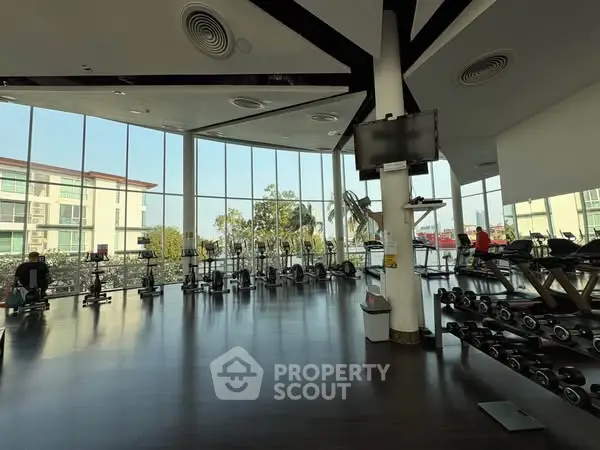 Spacious gym with modern equipment and large windows offering a scenic view.