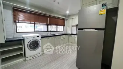 Modern kitchen with washing machine and large fridge in sleek apartment