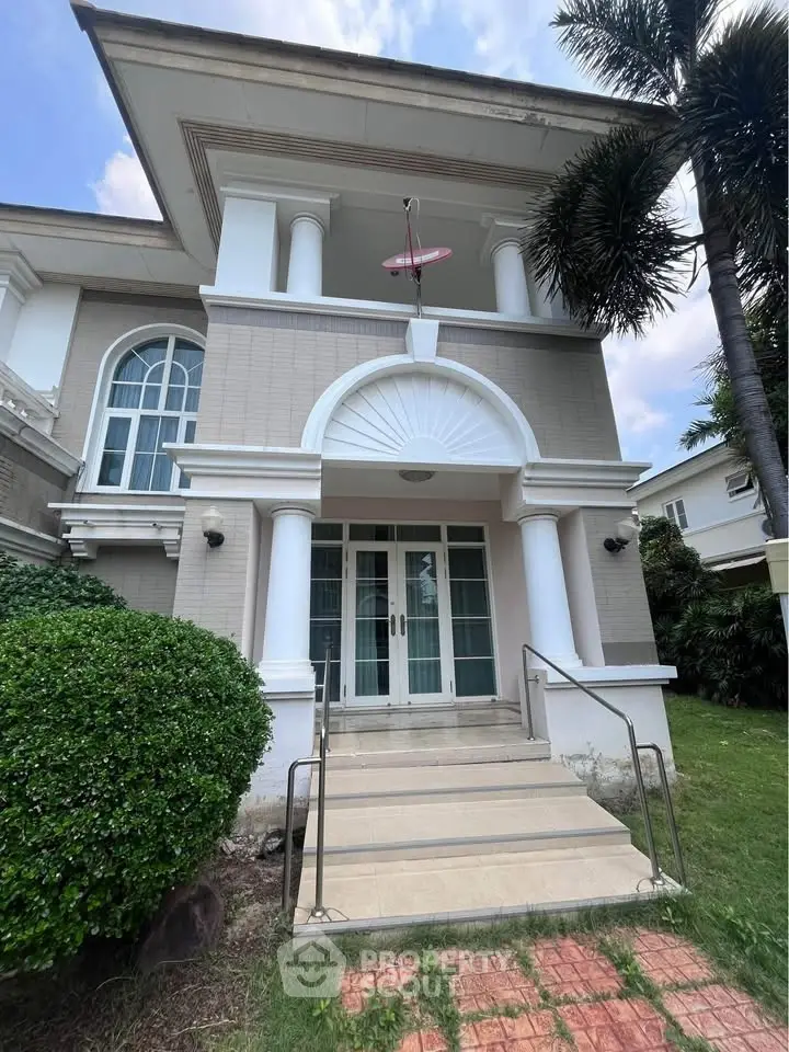 Elegant two-story house with grand entrance and lush greenery