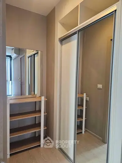 Modern storage area with mirrored sliding doors and wooden shelves in a stylish apartment.