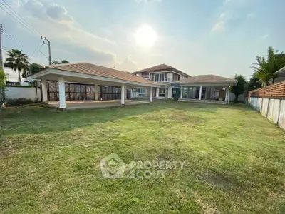 Spacious luxury home with expansive green lawn and modern architecture under a clear sky.