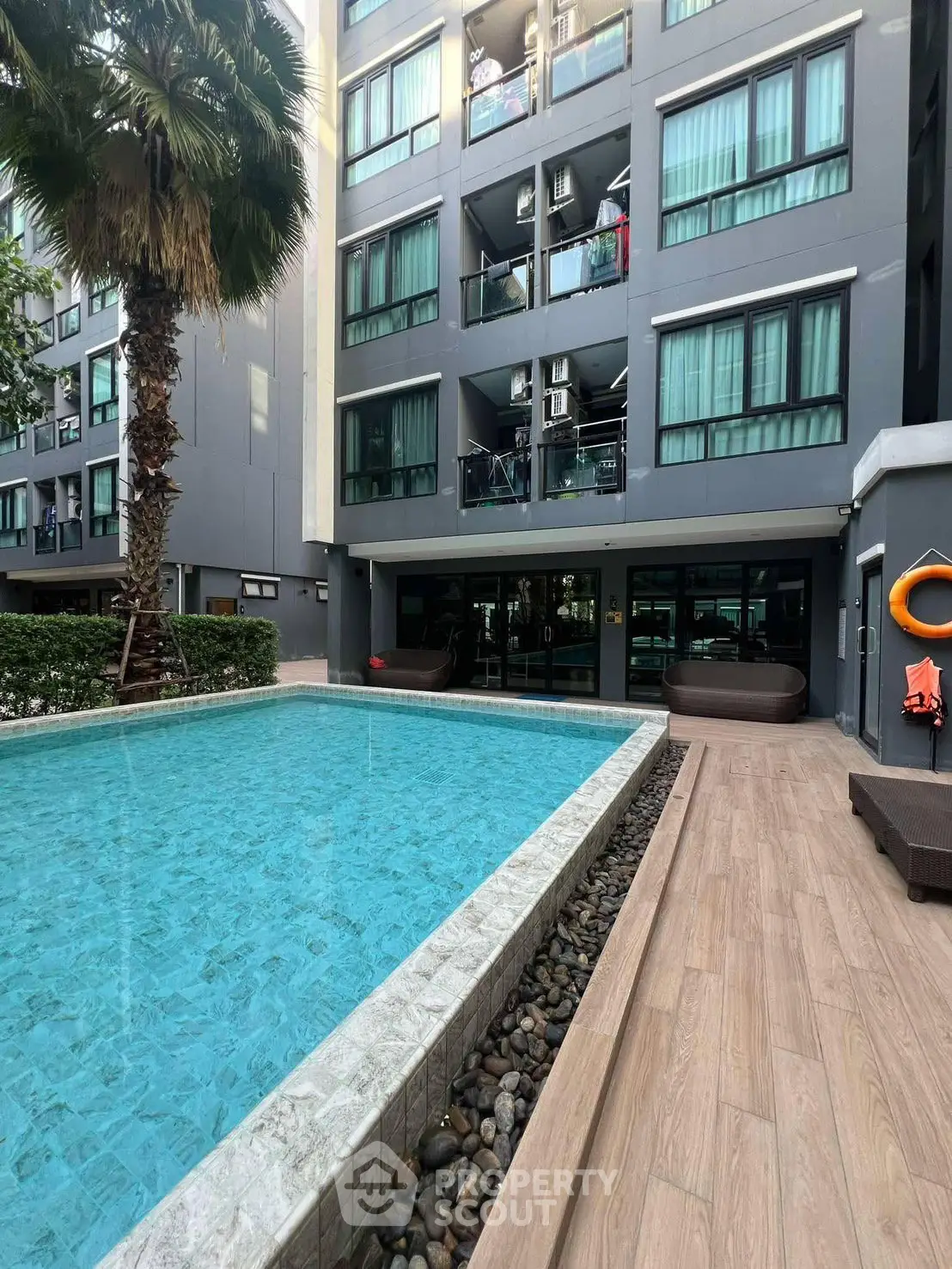 Modern apartment building with pool and palm tree, perfect for urban living.