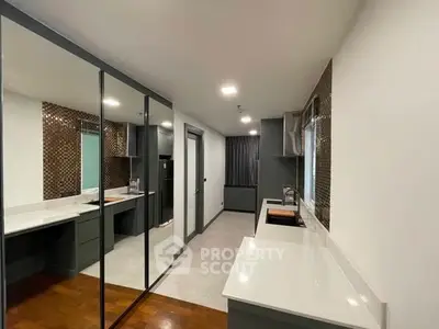 Modern kitchen with sleek cabinetry and mirrored wall for spacious feel