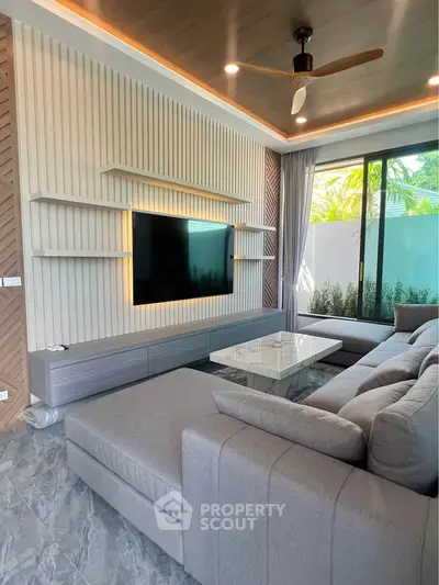 Modern living room with stylish decor, large sectional sofa, and wall-mounted TV, featuring floor-to-ceiling windows.