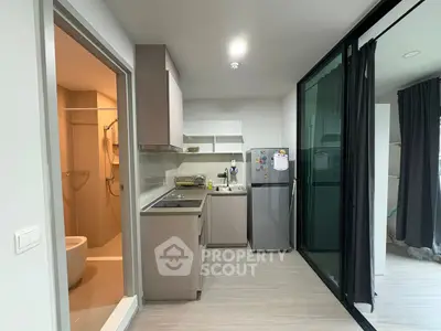 Modern compact kitchen with sleek cabinetry and adjacent bathroom, ideal for urban living.