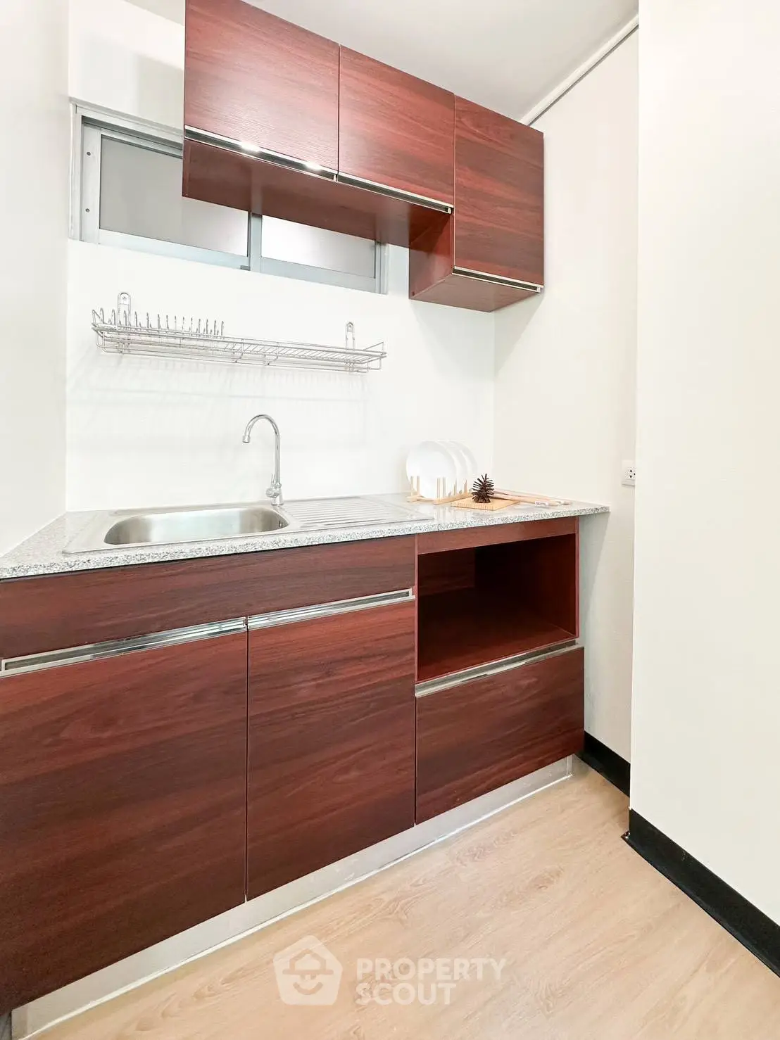 Modern kitchen with sleek wooden cabinets and stainless steel sink in a compact layout.