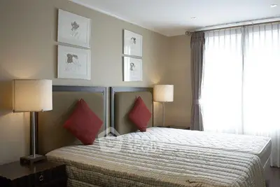Elegant bedroom with twin beds, stylish decor, and natural light from large window.
