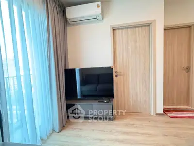 Modern living room with large TV and air conditioning, featuring elegant curtains and wooden flooring.